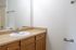 Bright and inviting bathroom with oak cabinetry, sleek modern fixtures, and a large mirror reflecting ample light.