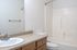 Bright and modern bathroom featuring a sleek countertop, elegant sink, and a tiled shower area.