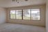 Bright and airy apartment room with large windows showcasing a scenic neighborhood view, perfect for stylish living.
