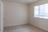 Bright and inviting bedroom with large window, beige carpet, and soft beige walls.