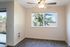 Bright and inviting dining nook with large window and ceiling fan, overlooking lush greenery.