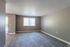 Bright, spacious living room with modern gray flooring, large window, and neutral walls, perfect for customization.