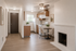 Cozy apartment interior featuring a modern kitchen with wooden cabinets, a quaint dining area, and a charming white brick fireplace, complemented by sleek wood flooring.