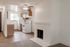 Bright and airy apartment kitchen with modern wooden cabinets, white appliances, and a cozy white brick fireplace.