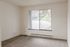 Bright apartment room featuring large window with scenic rooftop and treetop views.