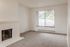 Inviting living room with cozy brick fireplace and large window offering natural light and scenic views.