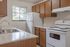 Bright kitchen with sleek countertops, modern appliances, and wooden cabinetry, offering a cozy culinary space with a view.