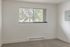 Bright, airy room with a large window, offering serene views of lush greenery.