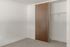 Bright and inviting bedroom featuring a spacious closet with sleek wooden sliding doors and fresh white walls.