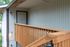 Inviting wooden porch leading to a stylish modern apartment entrance with charming vertical siding.