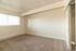 Bright and airy room with neutral tones, plush carpeting, and ample natural light through wide windows, offering a cozy and inviting ambiance.