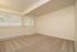 Spacious room with neutral carpet and large windows featuring vertical blinds, creating a bright and inviting atmosphere.