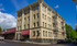 Charming vintage apartment building with classic architecture, red awnings, and fire escape, nestled in a vibrant urban setting.