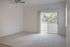 Bright and airy room with plush carpet and sliding glass doors leading to a scenic balcony, perfect for relaxation.