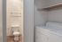 Modern apartment with a pristine laundry area adjacent to a sleek bathroom, featuring contemporary design and efficient use of space.