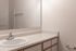 Bright and modern bathroom showcasing a sleek countertop, large mirror, and stylish fixtures.