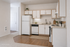 Bright and airy kitchen featuring modern white cabinetry, sleek countertops, and elegant wood flooring.