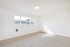 Bright, spacious room with large window and plush carpeting, perfect for personalization in a modern apartment.