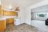Bright open-plan kitchen and living space with modern wooden cabinetry, sleek countertop, and large window views.