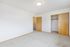 Bright and spacious bedroom featuring plush carpeting, ample closet space, and elegant wooden doors.