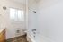 Bright bathroom featuring a modern bathtub, tiled flooring, and a large window illuminating the space.
