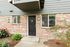 Charming apartment entrance with elegant black door, brick facade, and welcoming garden accents.