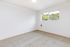 Inviting bright and airy room with plush carpet, large window, and tranquil views, ideal for restful living.