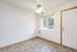 Bright and welcoming room with elegant tile flooring, large window, and ceiling fan, perfect for a cozy living area.