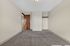 Bright and spacious bedroom with plush carpet, a wooden door, and an open closet concept.