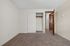 Bright and spacious bedroom with cozy carpeting, featuring a large closet and sleek wooden doors, ideal for stylish living.