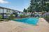 Inviting outdoor swimming pool surrounded by lush greenery and charming apartment buildings, offering a serene and relaxing community environment.