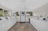Spacious and bright laundry room with modern washing machines, featuring large windows and sleek wood flooring.