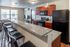 Modern open-concept kitchen and living area with sleek granite countertops, stylish bar stools, and stainless appliances, offering a bright and welcoming space for relaxation and entertainment.