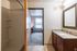 Inviting apartment bathroom with a modern shower, elegant granite vanity, and a view into a cozy, naturally lit bedroom.