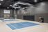 Modern indoor basketball court with sleek design, featuring cozy seating area and ball storage rack.