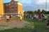 Vibrant outdoor volleyball game with a lively crowd in front of a charming brick apartment building, creating a sense of community and fun.