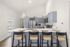 Bright modern kitchen featuring elegant pendant lights, sleek gray cabinetry, and a stylish breakfast bar with seating for four.