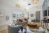 Bright, inviting living room featuring modern decor, cozy seating, woven pendant lights, and large windows overlooking a beautiful pool area.