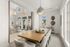 Elegant modern dining area featuring a long wooden table surrounded by plush chairs, large windows inviting natural light, and stylish pendant lighting.