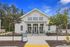 Inviting leasing center for modern villas, showcasing charming white architecture framed by lush greenery and a clear blue sky.