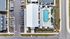 Aerial view of a modern apartment complex featuring a luxurious swimming pool with lounge areas, surrounded by green spaces and ample parking.