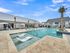 Luxurious outdoor pool area with sleek lounge chairs and umbrellas, set against a modern clubhouse backdrop, perfect for relaxation and enjoyment.