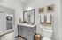 Bright and inviting bathroom featuring modern gray cabinetry, elegant framed artworks, and thoughtfully arranged greenery for a fresh look.