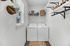 Bright laundry room with modern washer and dryer, stylish wall shelves, and charming plant decor.
