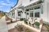 Charming townhouse exterior with elegant porch seating, lush potted plants, and inviting modern design on a sunny day.
