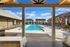 Inviting outdoor swimming pool area with sun loungers, surrounded by modern buildings and blue skies, perfect for relaxation and leisure.