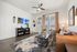 Elegant living room with a cozy leather sofa, chic glass coffee table, stylish decor, and large windows allowing natural light.