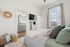 Bright bedroom with elegant decor, featuring cozy bed with plush pillows, modern wall-mounted TV, and en-suite bathroom showcasing stylish gray vanity.