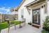 Charming outdoor patio with modern furniture, lush artificial grass, and stylish hanging chairs, perfect for relaxation and entertaining.