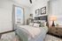 Elegant bedroom with chic decor, featuring a cozy bed with plush pillows, ambient lighting from a stylish lamp, and abundant natural light through large windows.